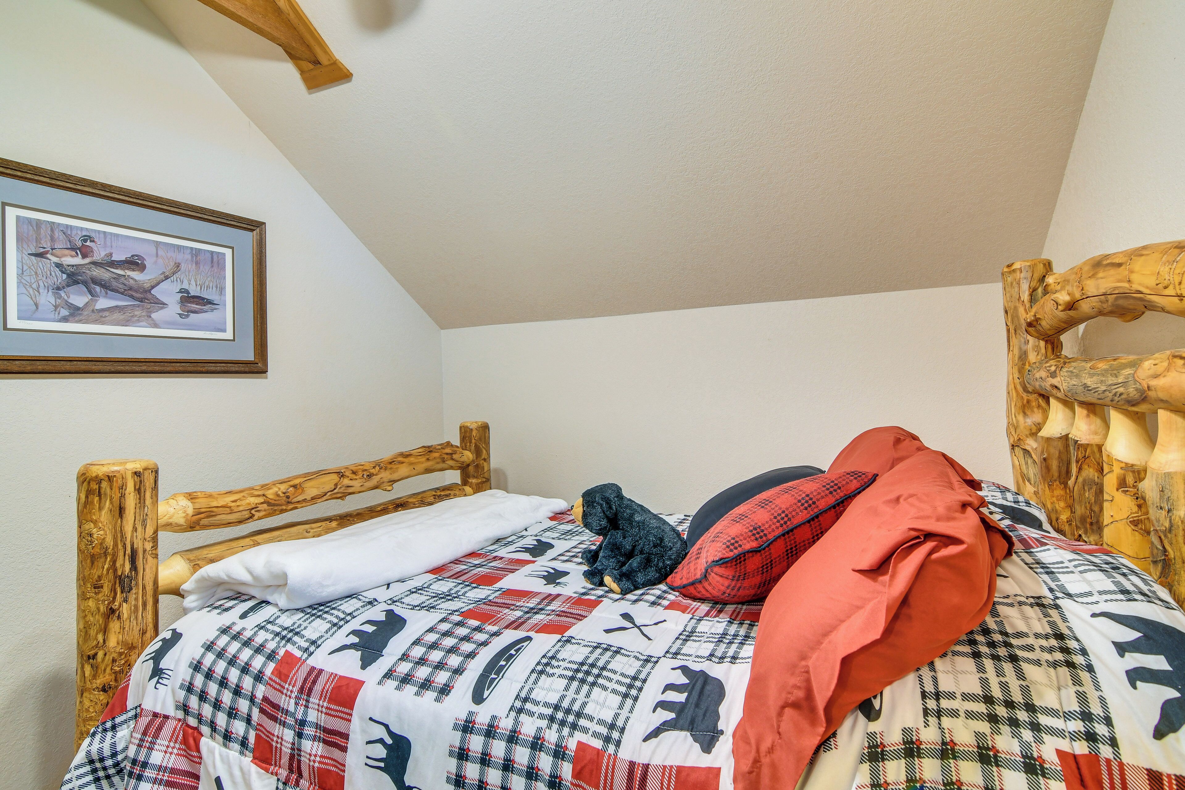 A bedroom with a wooden headboard, a plaid bedspread, and a framed picture on the wall.