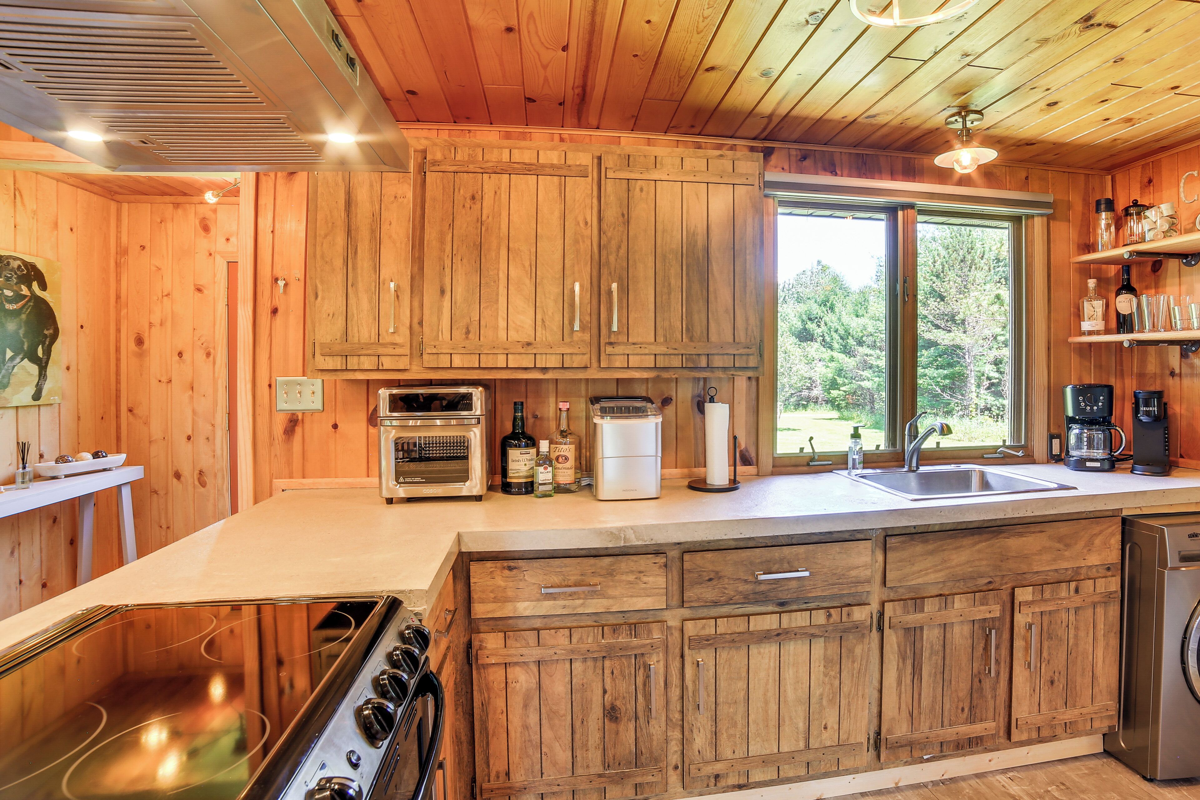 A wooden cabin kitchen with a stove, oven, sink, and built-in cabinets.