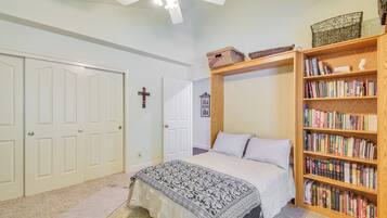 A bedroom with a bed, a bookshelf, a ceiling fan, and a door with a cross on it.