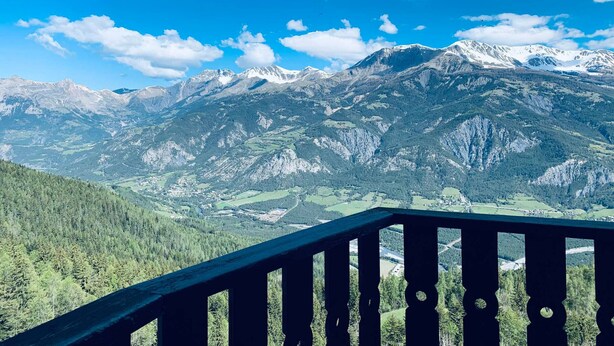 Un paysage de montagne avec une balustrade en bois sur un balcon.