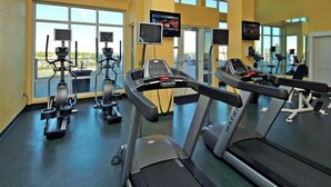 Un gimnasio con cintas de correr, bicicletas estáticas y elípticas.