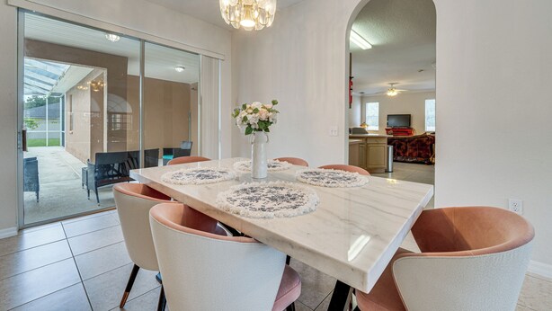 Un coin repas avec une table en marbre, des chaises en osier et un lustre.