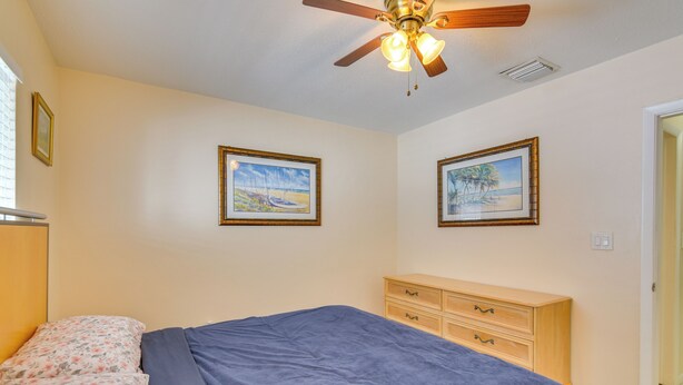A bedroom with a bed, a ceiling fan, and two framed pictures on the wall. - Pet-friendly Hallandale Beach Condo Near Boardwalk (Hallandale Beach)