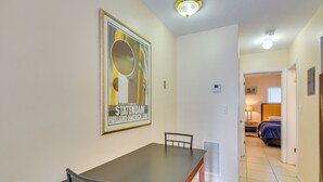 A hallway with a dining table and chairs, a framed poster on the wall, and a bedroom visible in the background. - Pet-friendly Hallandale Beach Condo Near Boardwalk (Hallandale Beach)