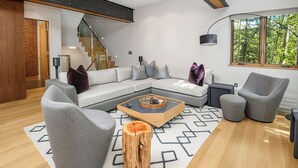 Uma sala de estar moderna com um sofá seccional, poltronas cinzas e uma mesa de centro.