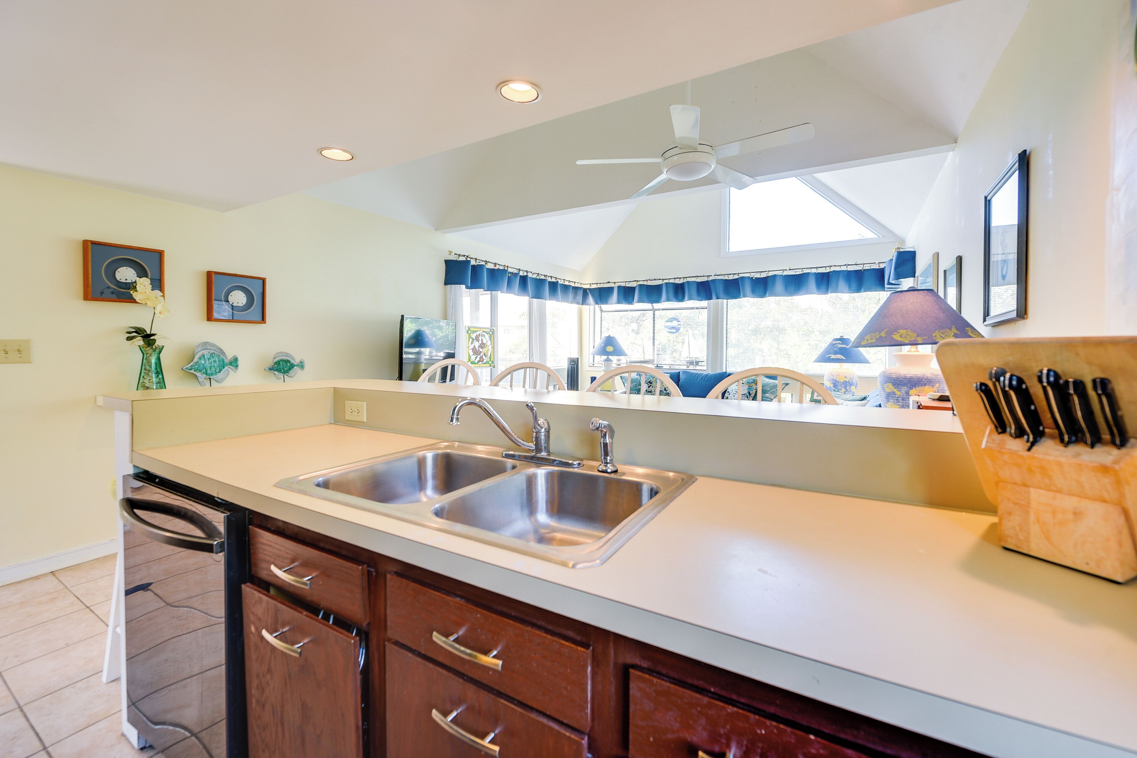 A kitchen with a double sink, wooden cabinets, and a ceiling fan.