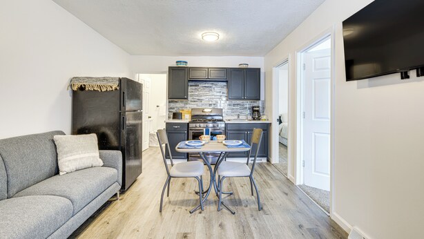 A compact living space with a kitchenette, a gray sofa, and a dining area with two chairs. - Walkable Barberton Apartment: 9 Mi to Akron! (Barberton)
