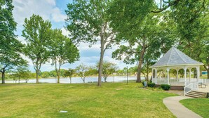 A gazebo with a white roof and white railings, surrounded by a grassy park area with trees and a lake in the background. - Walkable Barberton Apartment: 9 Mi to Akron! (Barberton)
