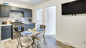 A compact kitchen with dark cabinets, a built-in stove, and a flat-screen TV mounted on the wall. - Walkable Barberton Apartment: 9 Mi to Akron! (Barberton)