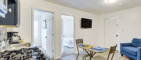 A kitchen with a gas stove, a sink, and a dining area with a table and chairs.