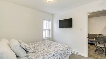 A bedroom with a bed, a TV mounted on the wall, and a window.