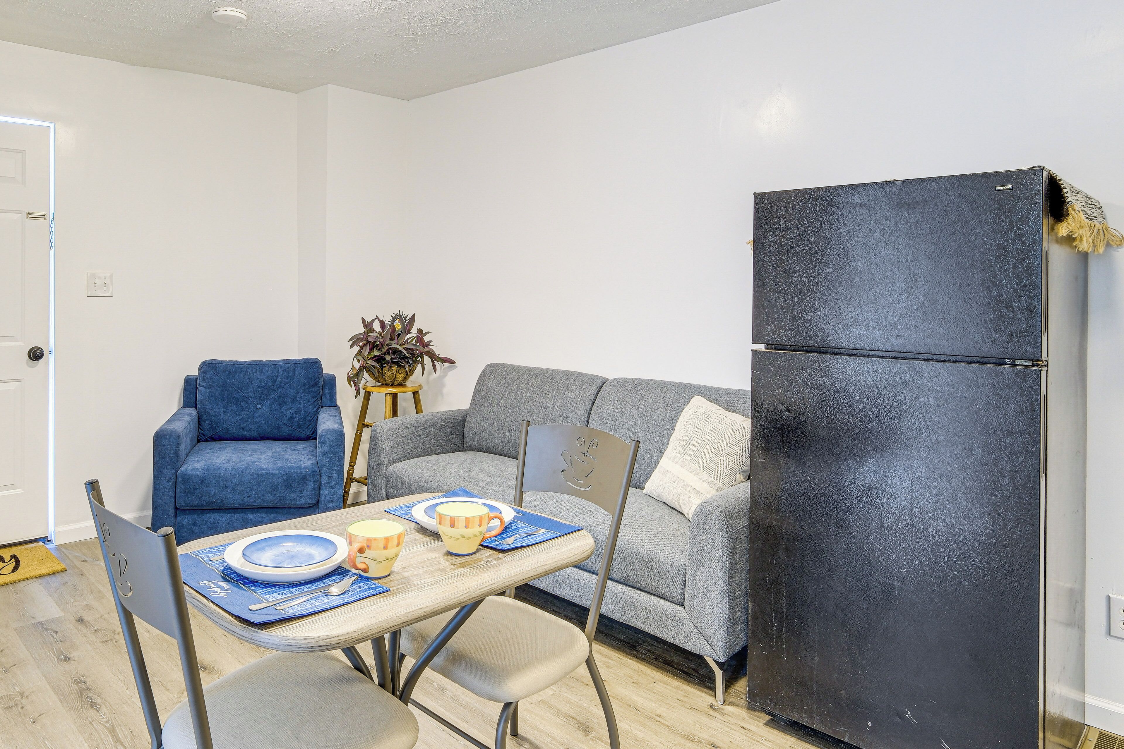 Un espacio habitable compacto con una mesa de comedor, sillas, un sofá y un refrigerador negro.