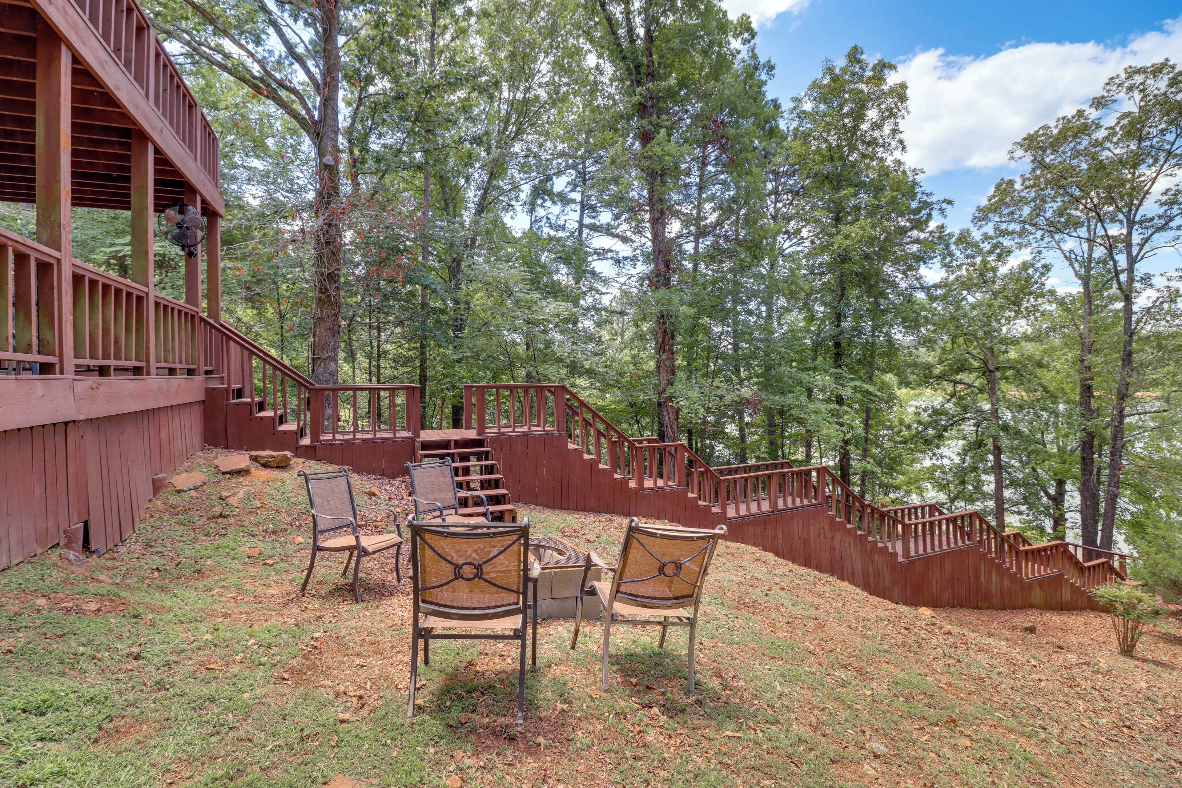 A wooden deck with outdoor seating and a staircase leading into a forest.