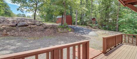 A wooden deck with a stone wall and a small building in a wooded area.