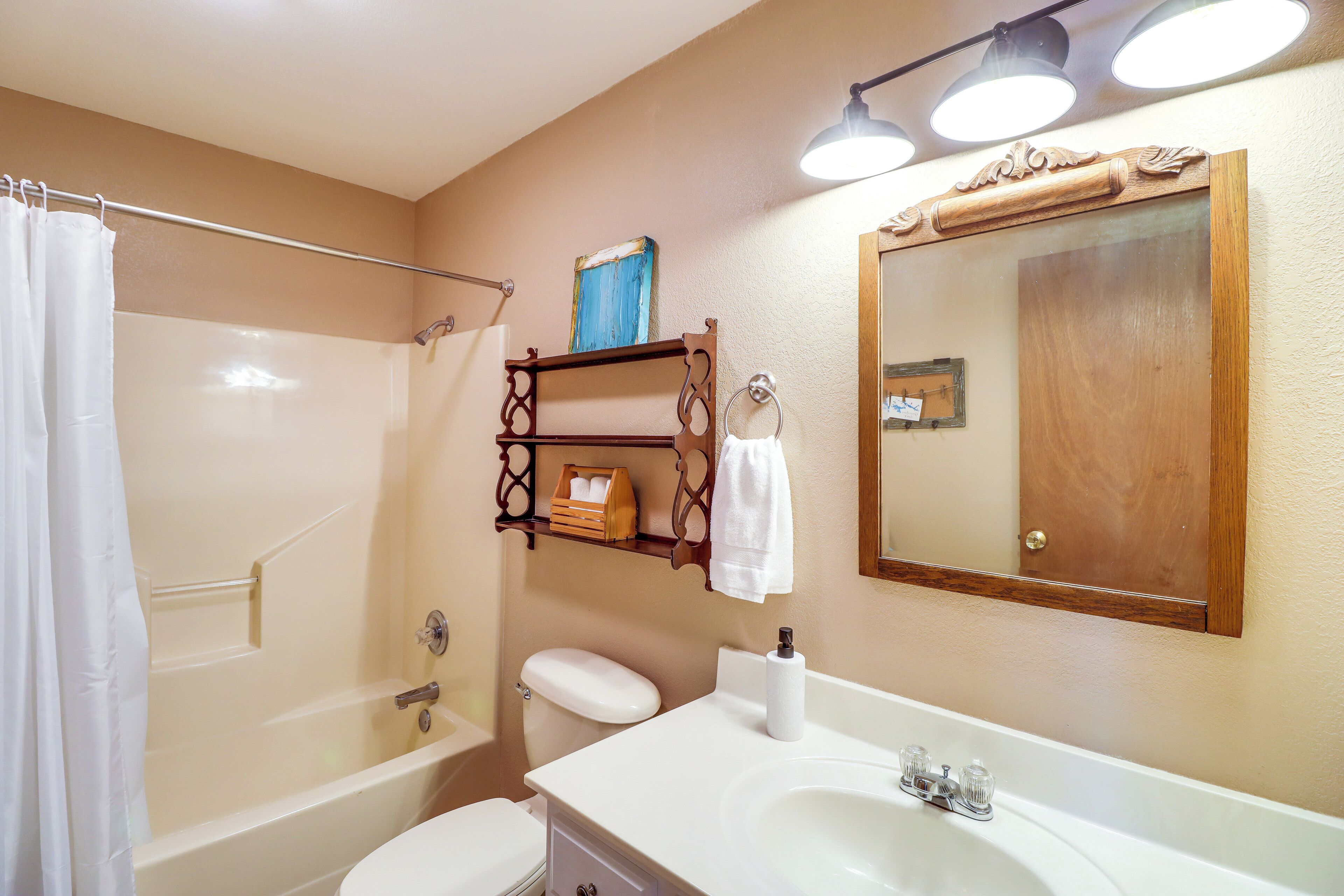A bathroom with a bathtub, toilet, and sink. There is a towel rack with towels and a mirror above the sink.