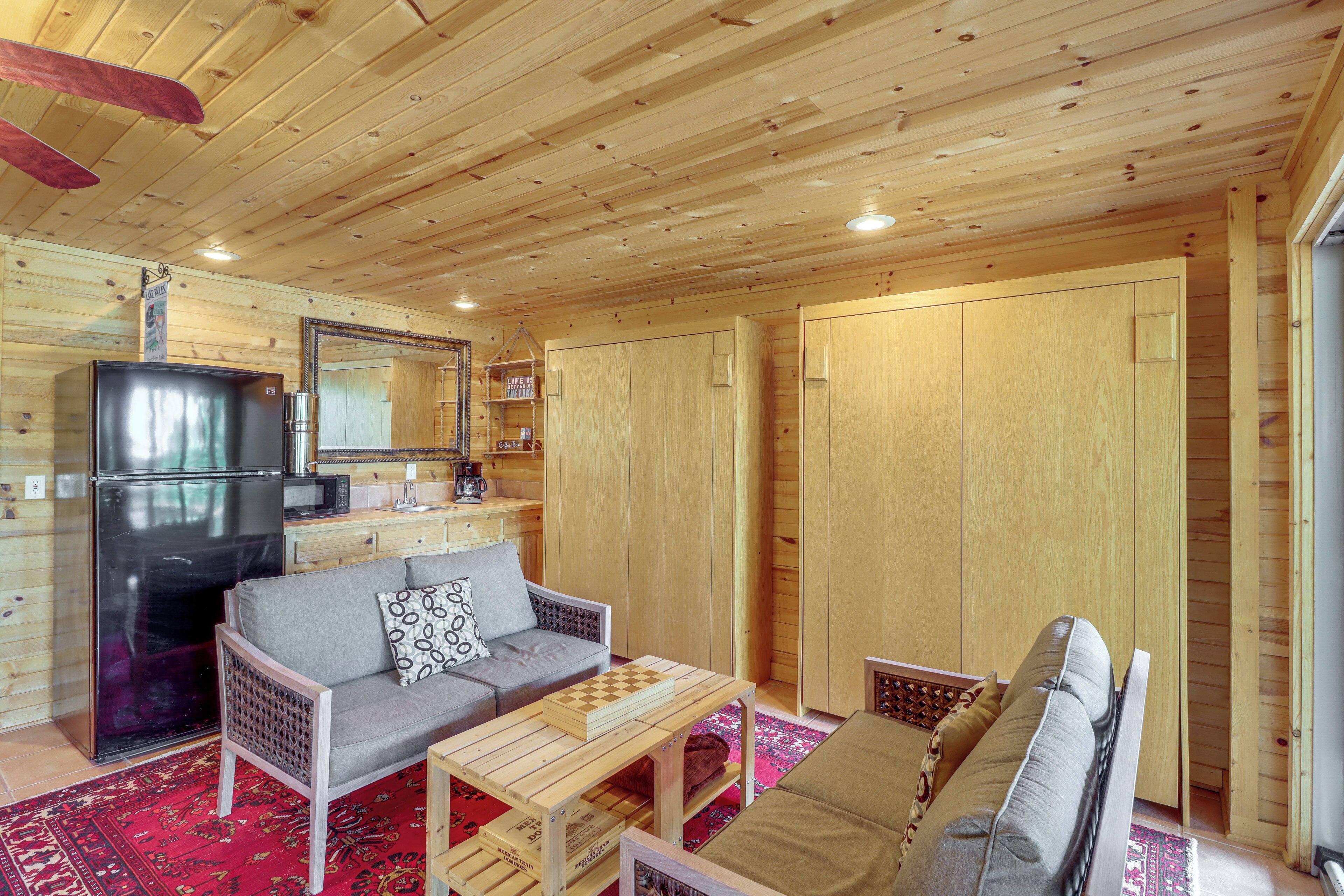 A wooden interior with a sofa, a coffee table, and a refrigerator.