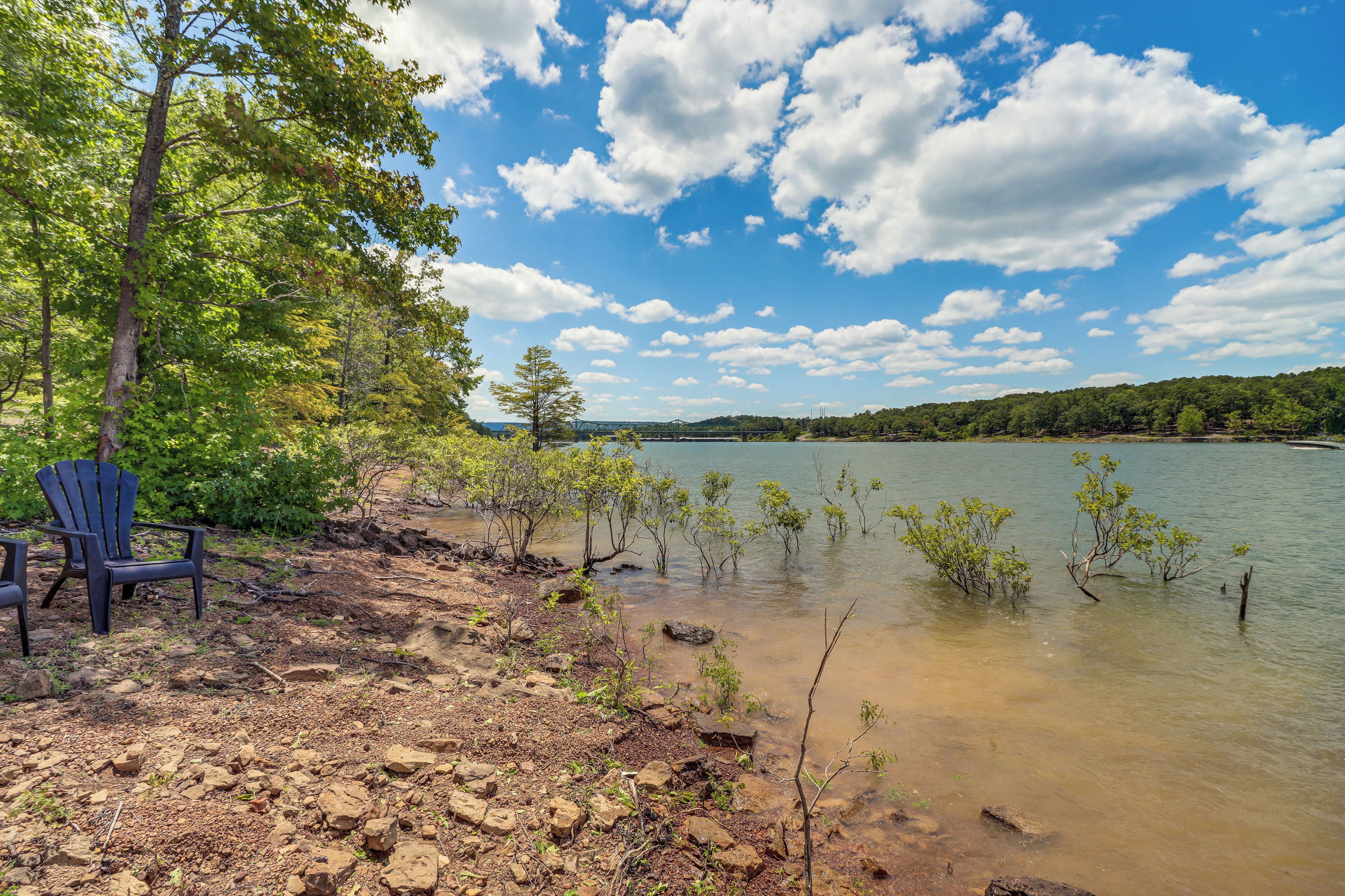 A lakeside view with chairs and a rocky shoreline.