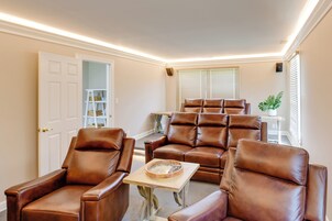 A room with a seating area featuring leather chairs, a small table, and a window with blinds.
