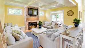 A living room with a fireplace, sofas, a coffee table, and a TV mounted on the wall.