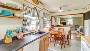 A kitchen with wooden cabinets, a black countertop, and a dining area with a wooden table and chairs. - Horses Welcome: Marble Falls Home w/ Grill! (Marble Falls)
