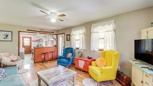 A living room with a sofa, armchairs, a coffee table, a television, and a kitchen area in the background. - Horses Welcome: Marble Falls Home w/ Grill! (Marble Falls)