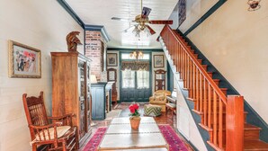 Un salon spacieux avec un escalier en bois, un lustre et une moquette rouge.