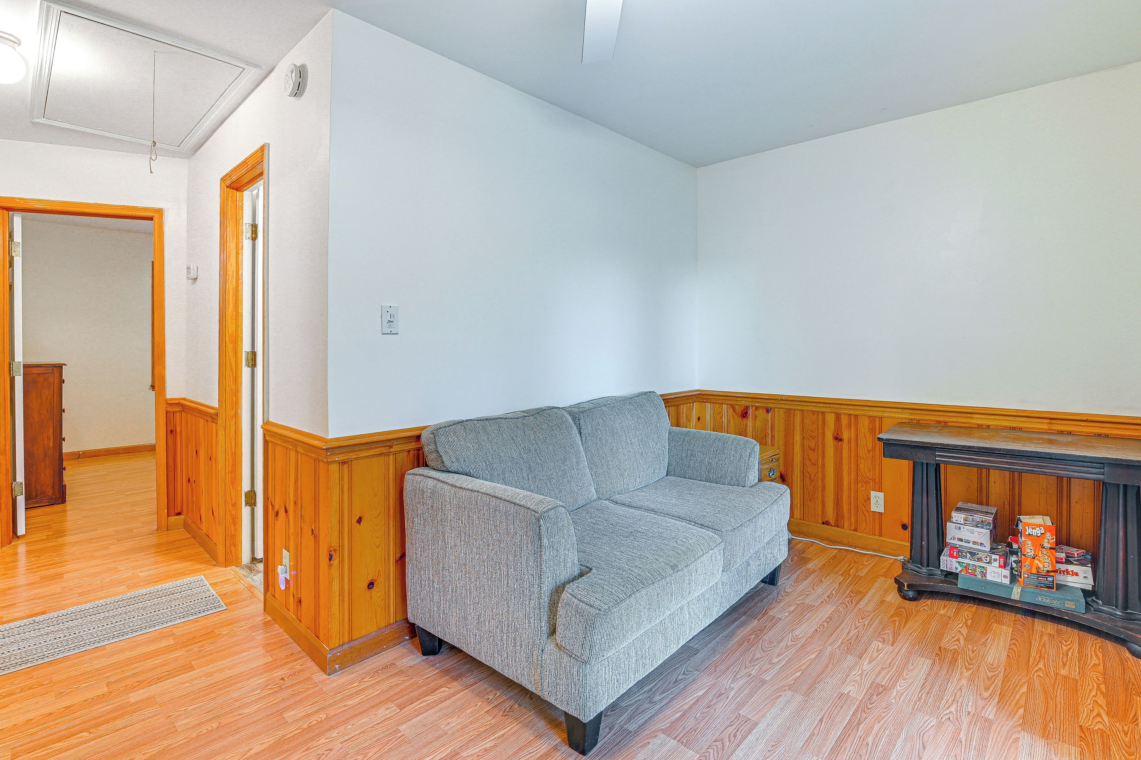 A room with a grey sofa, wooden paneling, and a dark wooden console table with boxes.