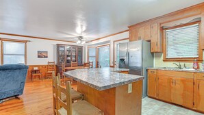 A spacious kitchen with wooden cabinets, a granite countertop island, and a dining area with chairs and a table. - Half Mile to Beach: Murrells Inlet Home w/ Deck! (Murrells Inlet)