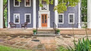 A two-story house with a front porch, stone steps, and a wooden door. - Quintessential New England Home w/ Patio & Grill! (Putnam)
