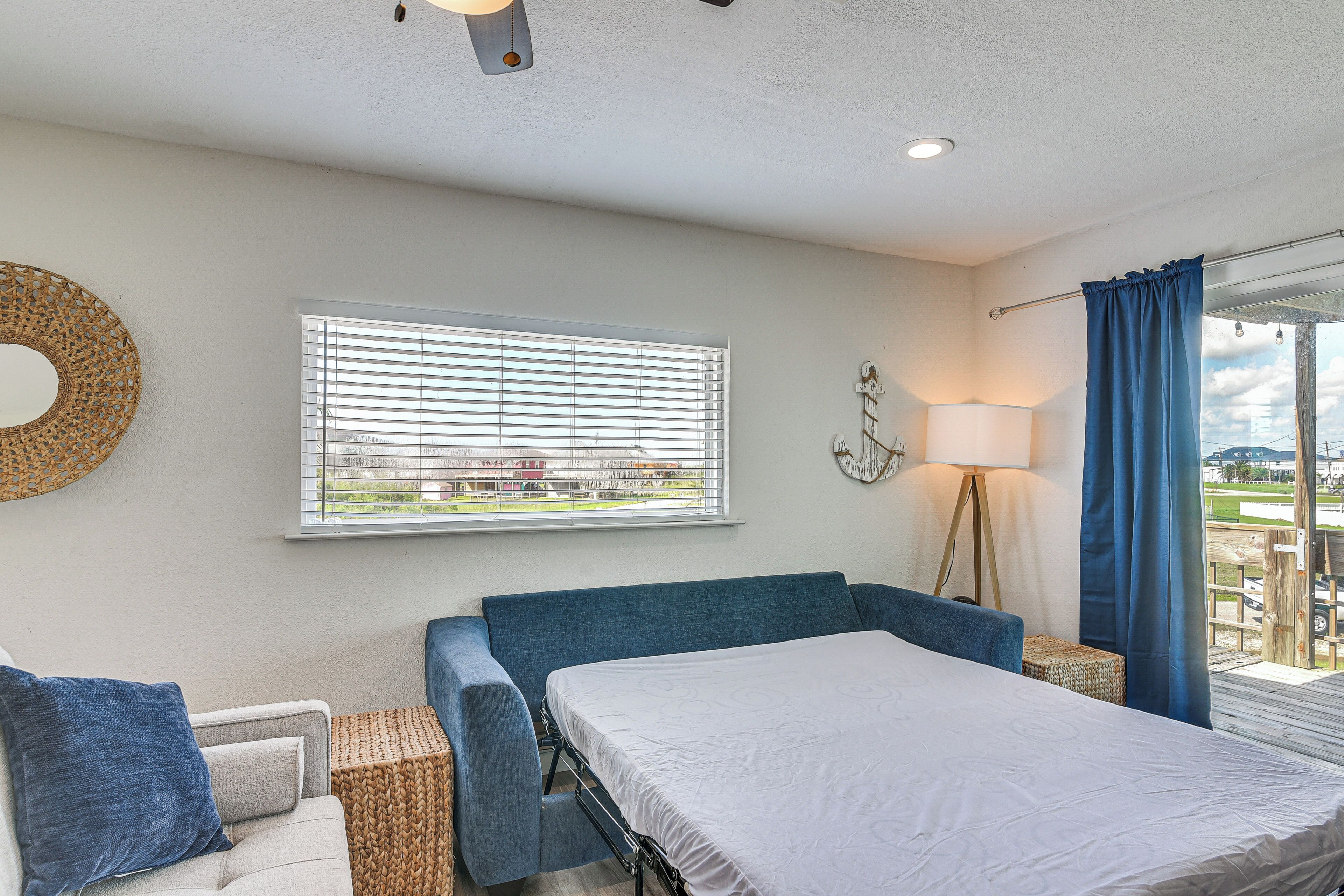 A bedroom with a bed, a sofa, a lamp, and a window with blinds.