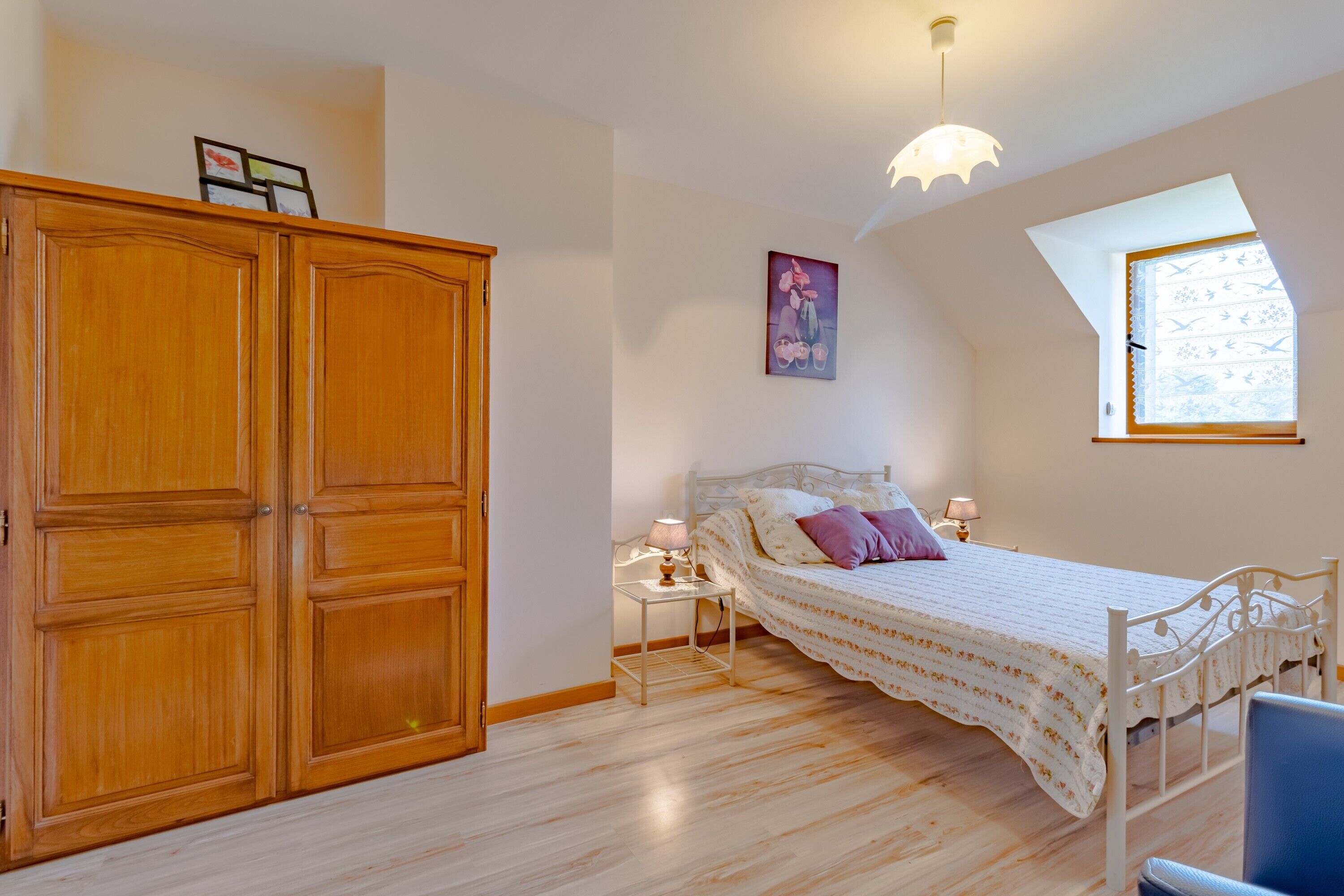 Une chambre à coucher comprenant un lit, une table de chevet, une armoire, une fenêtre et un luminaire au plafond.
