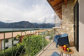 Un balcon avec vue sur les montagnes, une table avec des fruits et une chaise.