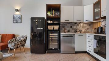 Eine kleine Küche mit Kühlschrank, Geschirrspüler, Backofen und einer Wandfliese mit Muster.