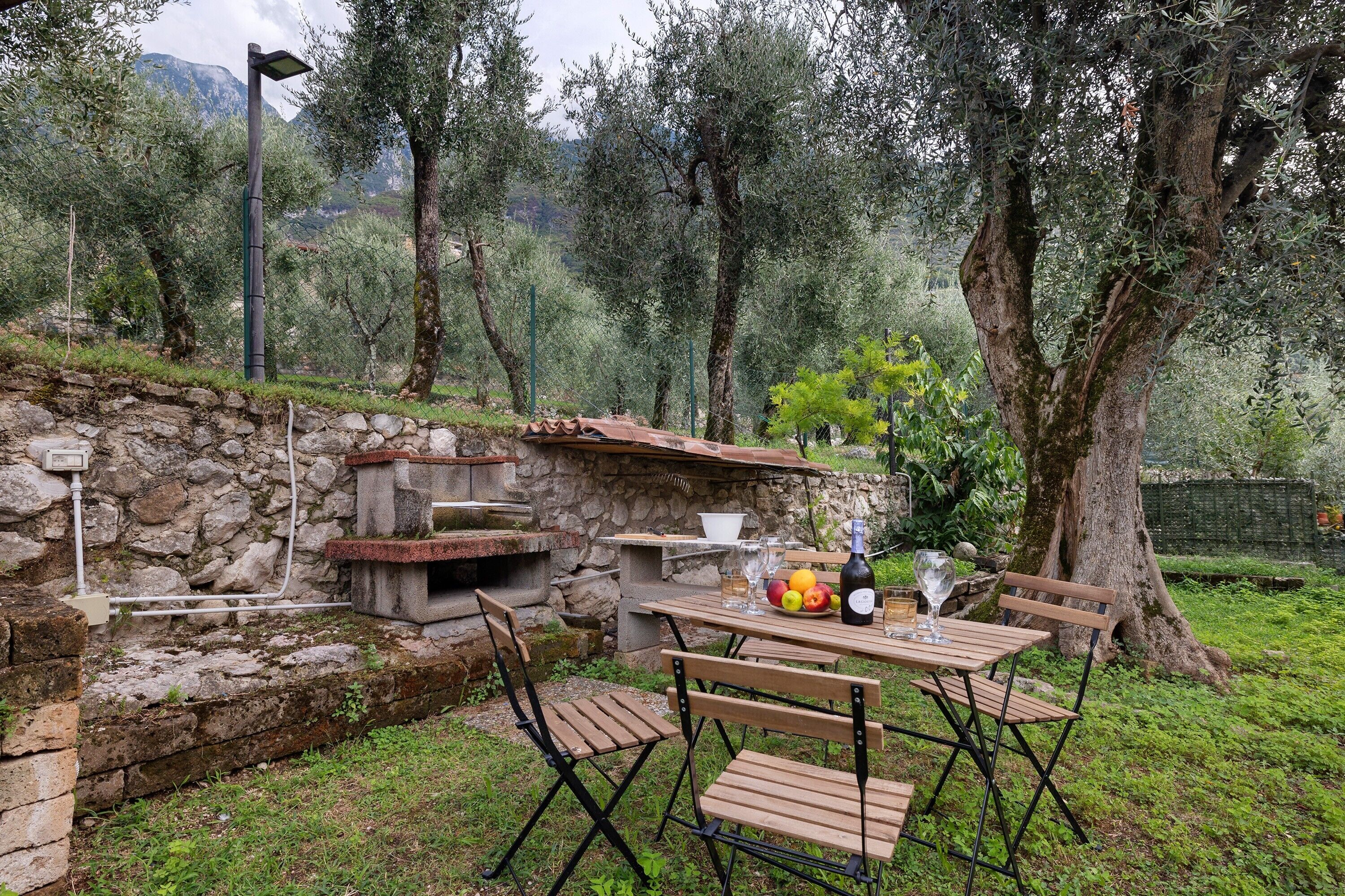 Un espace extérieur aménagé pour les repas, avec des murs en pierre, du mobilier en bois et un barbecue en pierre.