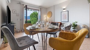 A dining area with a round table, chairs, and a view of greenery outside. - Holiday Home 'Casa Di Tino' with Lake View, Wi-Fi and Air Conditioning (Brenzone sul Garda)