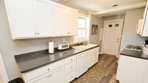 A kitchen with white cabinets, a black countertop, a microwave, a toaster, and a gas stove. - 3 blocks to Notre Dame, EV Charger, BBQ & Fire Pit! (1707) (South Bend)