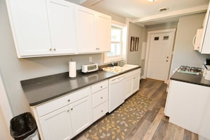 A kitchen with white cabinets, a black countertop, a microwave, a toaster, and a gas stove. - 3 blocks to Notre Dame, EV Charger, BBQ & Fire Pit! (1707) (South Bend)