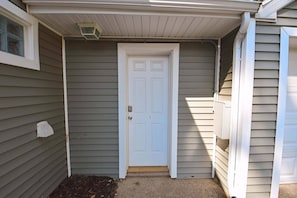 A house with a white front door, a small window, and a covered porch area. - 3 blocks to ND, EV Charger, BBQ & Fire Pit! (1707) (South Bend)