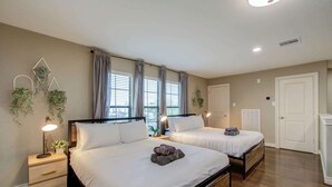 Une chambre avec deux lits, un plancher en bois et une table de chevet avec une lampe.