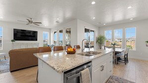 A modern kitchen with a granite countertop, built-in dishwasher, and a large island with a bowl of fruit. - The One by the Pool: Waterslide, Lazy River, Pickleball, Shuffleboard! (Washington)