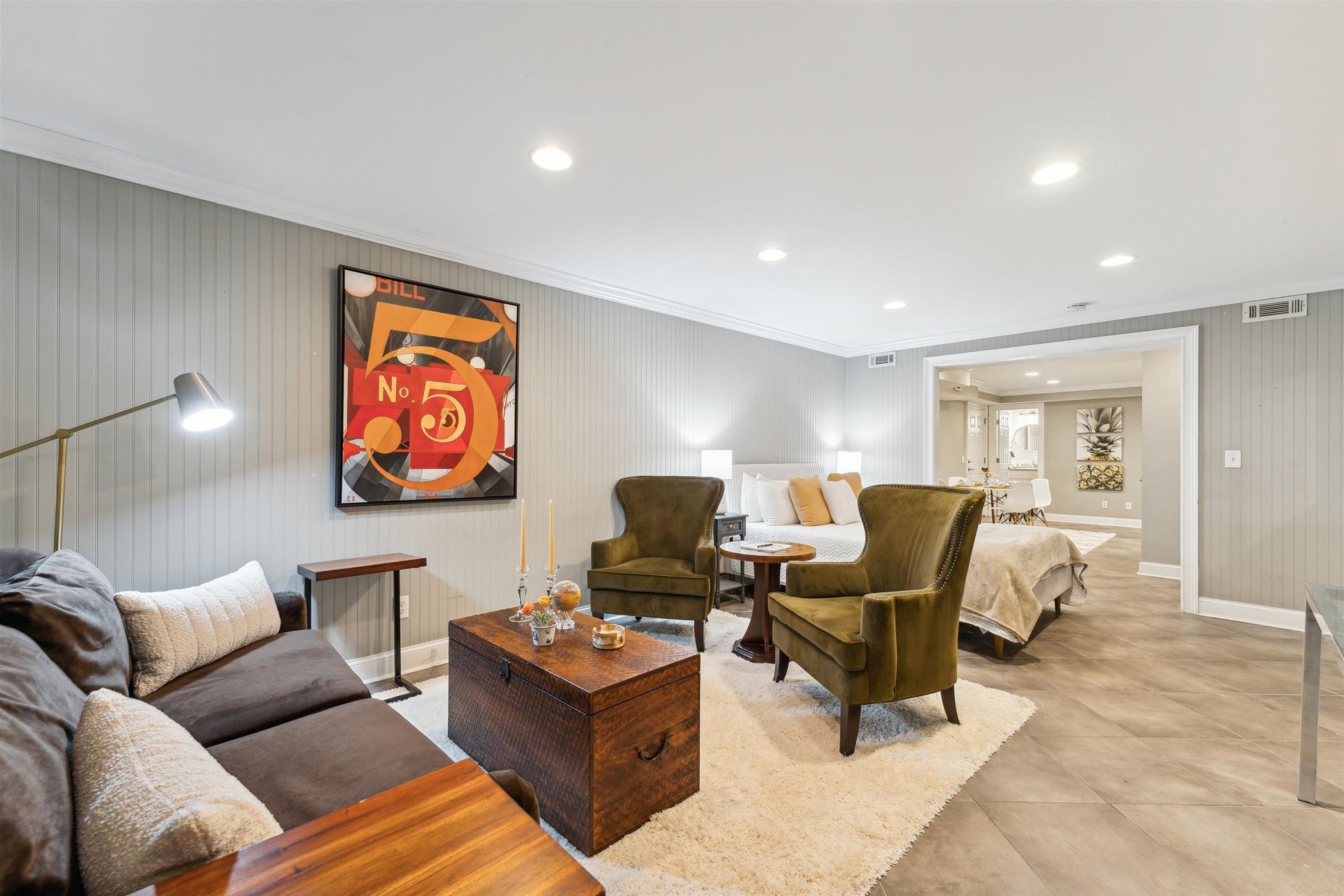 A modern living room with a sofa, armchairs, a coffee table, and a painting on the wall.