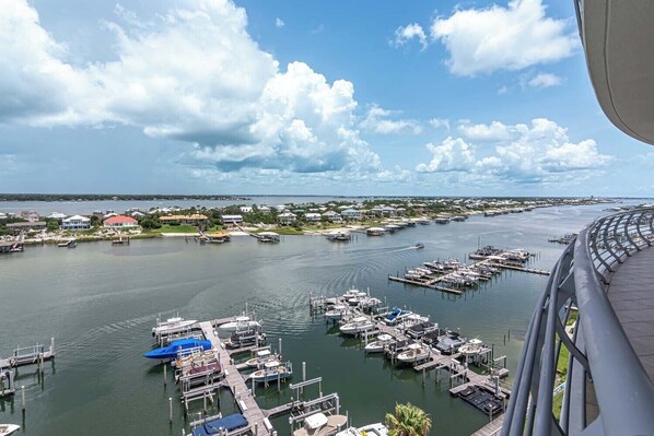 A marina with numerous boats docked at piers, surrounded by residential buildings and a clear sky.