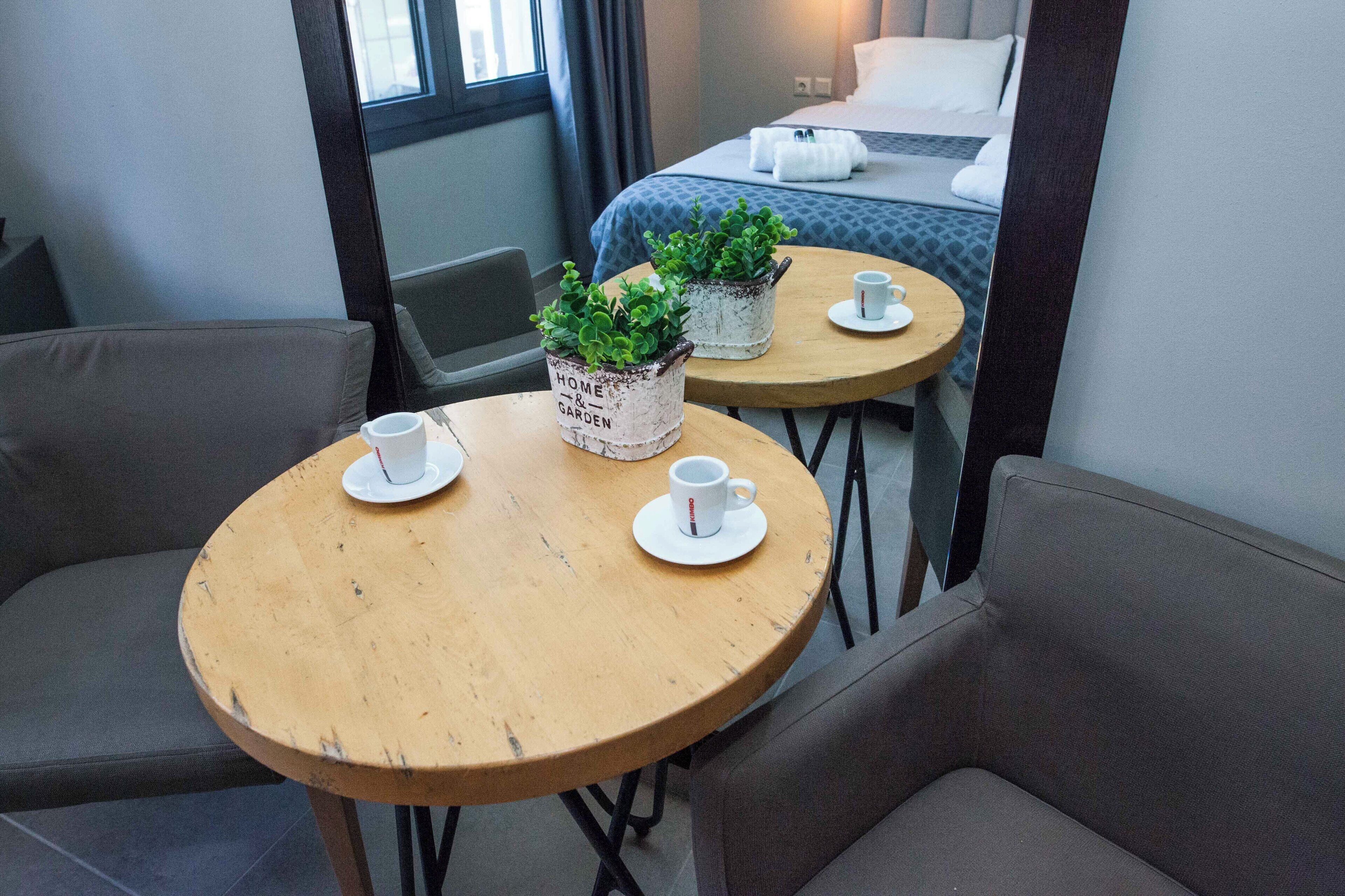 A cozy room with a bed, two small tables with potted plants, and two chairs.