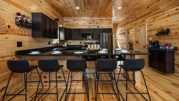 A modern kitchen with wooden walls and a central island with bar stools. - Otsego Lake Access Cabin, Fire Pit, Backyard & BBQ (Gaylord)