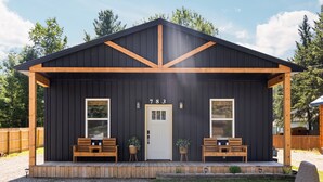A black wooden building with the number 783 on the door, two wooden benches, and a small garden area. - Otsego Lake Access Cabin, Fire Pit, Backyard & BBQ (Gaylord)