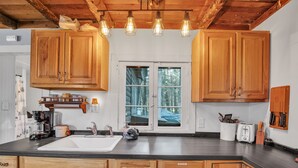 A kitchen with wooden cabinets, a black countertop, a sink, a coffee maker, and a toaster. - Rustic Willow Retreat - Outdoor Adventures 2 Bedroom Cabin by RedAwning (Hazelhurst)
