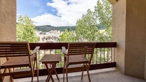 A balcony with two wooden chairs and a small table, overlooking a building and trees. - Strawberry Park #603 4 Bedroom Condo by RedAwning (Avon)