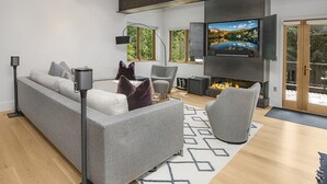 A modern living room with a grey sofa, a TV mounted on the wall, and a fireplace.