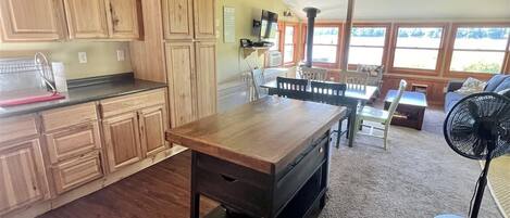 Un'ampia cucina con mobili in legno e un'isola grande, una zona pranzo con sedie e una ventola a soffitto.