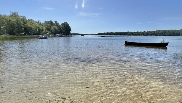 A clear lake with a boat in the distance, surrounded by trees and clear water. - Boomfish Limit 5 2 Bedroom Cottage by RedAwning (Windham)